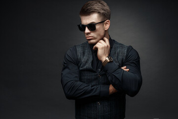 Portrait of beautyful guy on dark background. High fashion model posing in studio. Attractive man in classic suit.