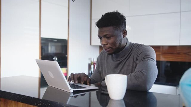 Young black man using laptop in his appartment. remote work concept. High quality 4k footage