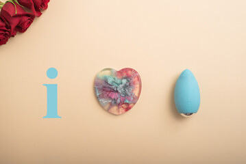Rose heart and clitoral vibrator on a beige background. Flat lay