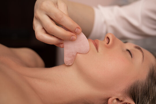 Young and beautiful woman during Chinese traditional massage - Gua Sha. Close-up photo. Beauty treatment in SPA salon