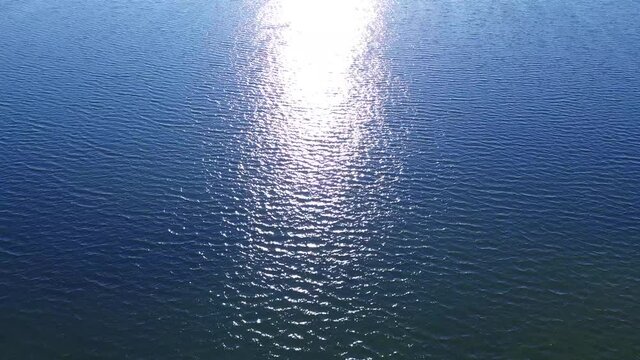 Calm blue sea view with waves and sun reflection