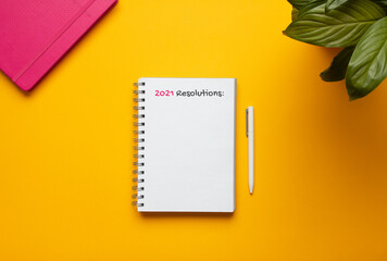 Stock photo of 2021 new year notebook with list of resolutions and objects on yellow background