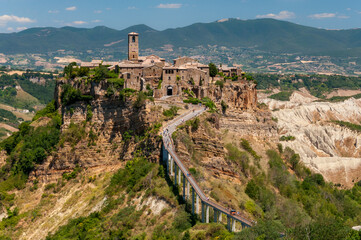 Fototapeta na wymiar Civita di Bagnoregio, Italy: beautiful view of famous Civita di Bagnoregio with Tiber river valley and the pathway bridge that leads to the ancient town on top of an eroding hill