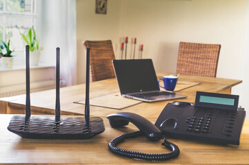 Black phone and black wi-fi router on wooden table. Home office concept. - obrazy, fototapety, plakaty