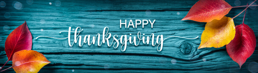 

"Happy Thanksgiving" Message On Rustic Blue Harvest Table Background Decorated With Leaves 