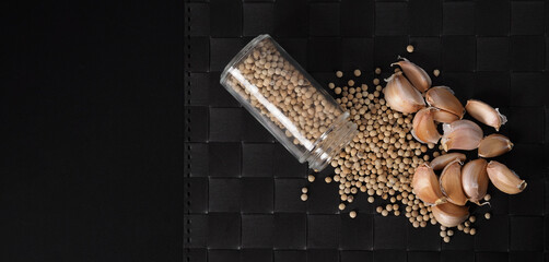 Natural Garlic and white peppercorn in glass bottle on plate mat black background in studio shot. It is main ingrediant for many asian recipe menu such as Singapore Bak kut teh, Thailand’s Pad Thai