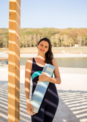 portrait of a cheerful yoga woman with a Mat on a sandy beach