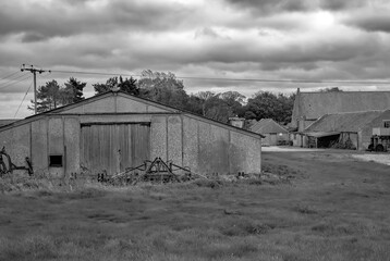 Fototapeta na wymiar Black and white photo of a farm yard, outhouses and buildings in rural Norfolk