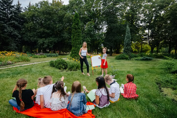 Obraz premium A teacher teaches a class of children in an outdoor Park. Back to school, learning during the pandemic
