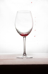 A glass of wine with a little bit of wine and a few drops of red on the outside