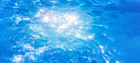 water in swimming pool background the surface of the water. texture, blue water, bright rays of the sun. web panorama banner with copy space.