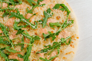 Pizza with salmon, parmesan and arugula isolated on white wooden background. Advert for social network of restaurants, caffee. Promotion for pizzeria