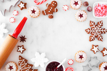 Christmas baking frame with cookies and sweets. Above view over a white marble background with copy...