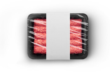 Sealable black plastic tray with white paper label filled with fresh raw beef kebabs top-view....