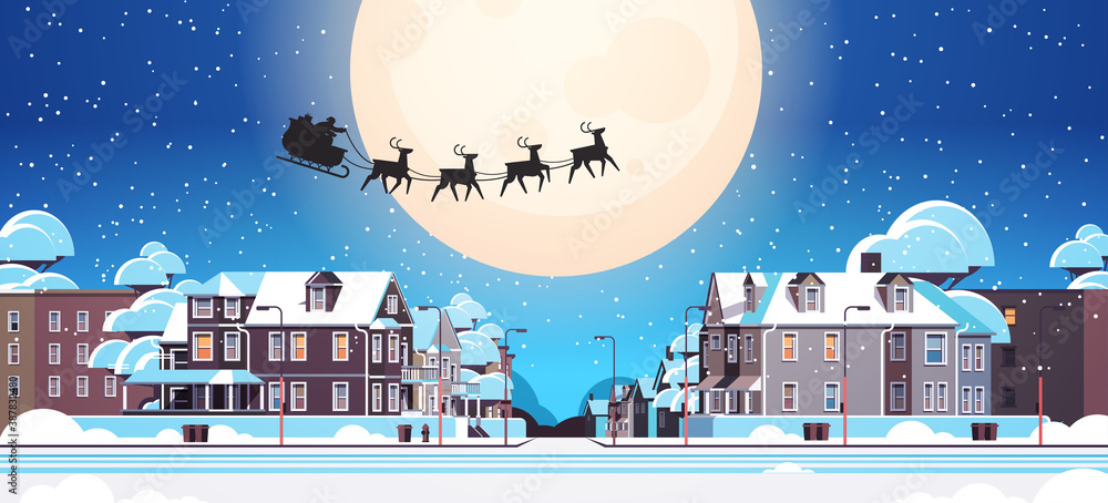 Wall mural santa flying in sledge with reindeers in night sky over village houses happy new year merry christma