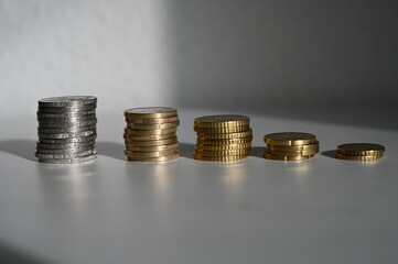 Stacked euro coins on a white desk.
