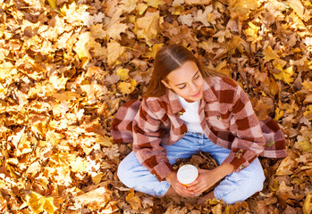 Portrait of young teenage girl lying in autumn foliage