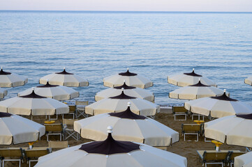 Colorful parasols on sandy beach of medieval small touristic coastal town Sperlonga, Latina, Italy on sunrise