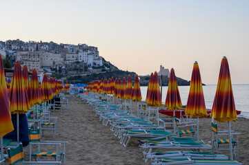 Colorful parasols on sandy beach of medieval small touristic coastal town Sperlonga, Latina, Italy...