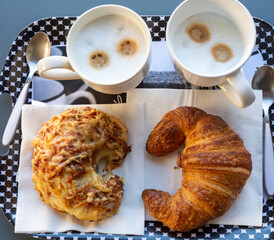 French breakfast in bakery served outdoor, cups of coffee and fresh baked croissants and pastry, morning food