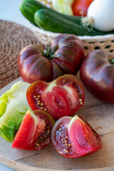 Obraz na płótnie Canvas Making green salad with big ripe raddish-purple heirloom tomatoes Black Crimea