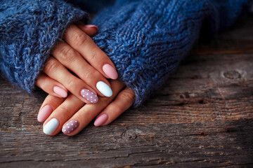 Women is hands with a beautiful manicure, in a knitted sweater on a wooden background in. Autumn...
