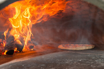 real Italian pizza margherita is cooking in a wood oven