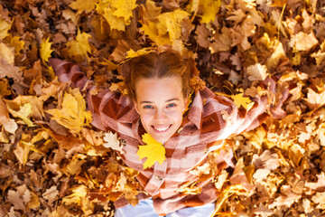Portrait of young teenage girl lying in autumn foliage