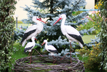 Stork family with four baby storks in a garden. Garden figurine. Concept of family