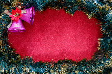 Christmas background. Christmas tree garland and a pair of holiday bells on a red shiny surface. Top view with a copy of the space. New year's background, holiday, Christmas