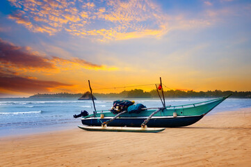 Fototapeta premium Against the background of the sunset sky and the ocean, an old fishing boat. Sri Lanka