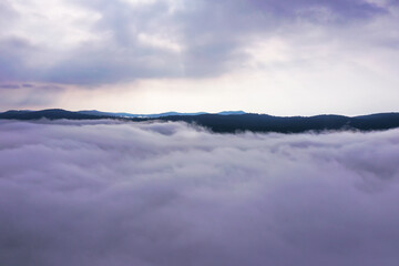 Fototapeta premium Aerial photo above fog. Beautiful sunrise through clouds. Hill tops in distance.