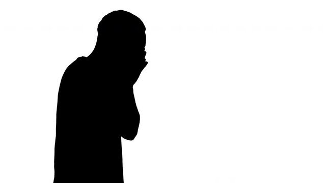 Silhouette Sleepy male in white t-shirt yawning and rubbing eyes while walking.