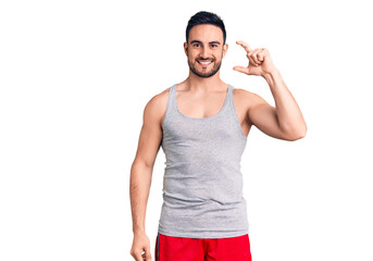 Young handsome man wearing swimwear and sleeveless t-shirt smiling and confident gesturing with...