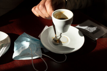 The hands of a man, holds a cup of coffee, while the afternoon light enters through the bar window, Luesia, Aragón, Spain.