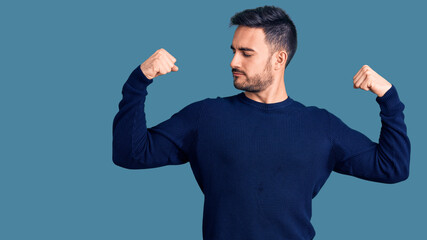 Young handsome man wearing casual clothes showing arms muscles smiling proud. fitness concept.