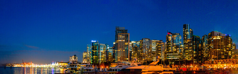 Fototapeta na wymiar View of Vancouver skyline with illuminated towers against blue sky