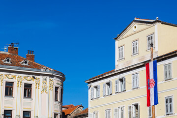 Fototapeta na wymiar Croatian flag contrasts against old buildings