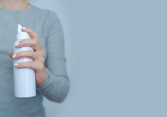 Woman holding nasal spray in hand on gray background