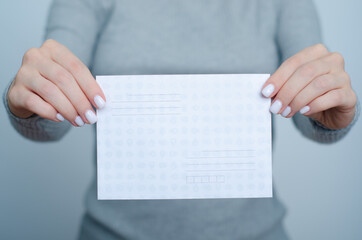 Woman holding Postal envelope in hand on gray background