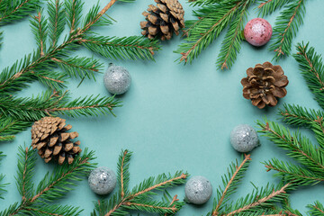Obraz na płótnie Canvas Fir, spruce branches, pine cones and Christmas tree toys on green background with copy space