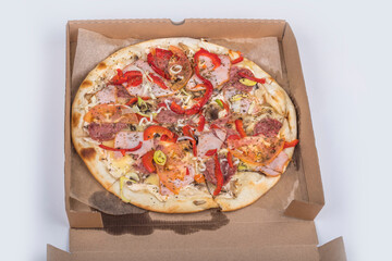 studio lighting. pizza in a paper box. There are traces of fat along the edges. On white background. Close-up.