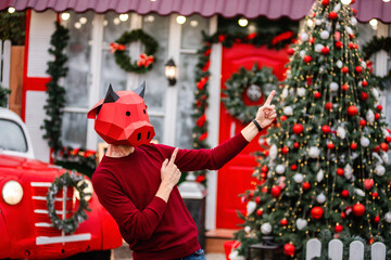A young man in a bull ox costume is a symbol of the new year against the background of a red car, a...