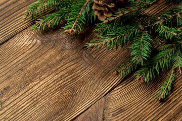 Fir, spruce branches on brown wooden background with copy space
