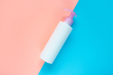 Bottle for liquid, cream, gel, lotion. Сosmetic bottle on blue and rose background. SPA cosmetic product branding mockup.
Flat lay minimalist style.