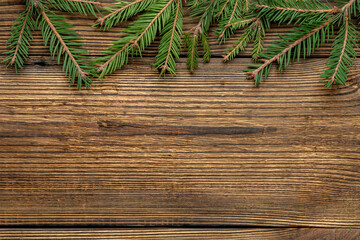 Fir, spruce branches on brown wooden background with copy space
