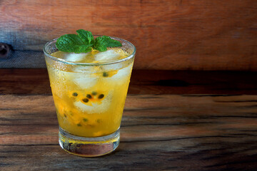 glass of passion fruit drink with mint leaf on rustic table