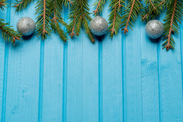Fir, spruce branches and Christmas tree toys on blue wooden background with copy space
