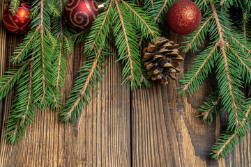 Fir, spruce branches, cones and Christmas tree toys on brown wooden background