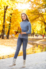 Full length portrait of a young beautiful girl posing in an autumn park